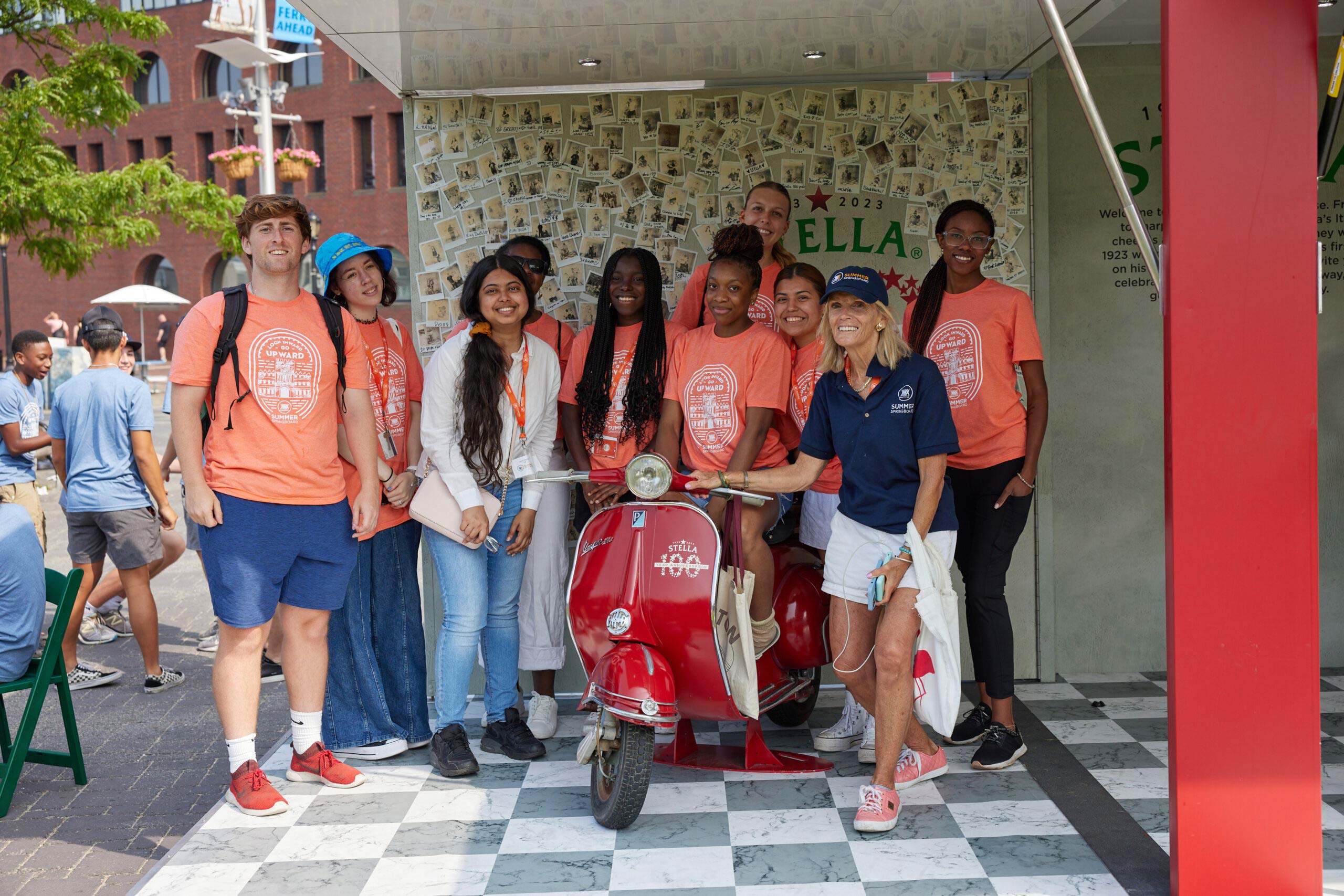 A group standing next to a Stella branded motorized scooter.