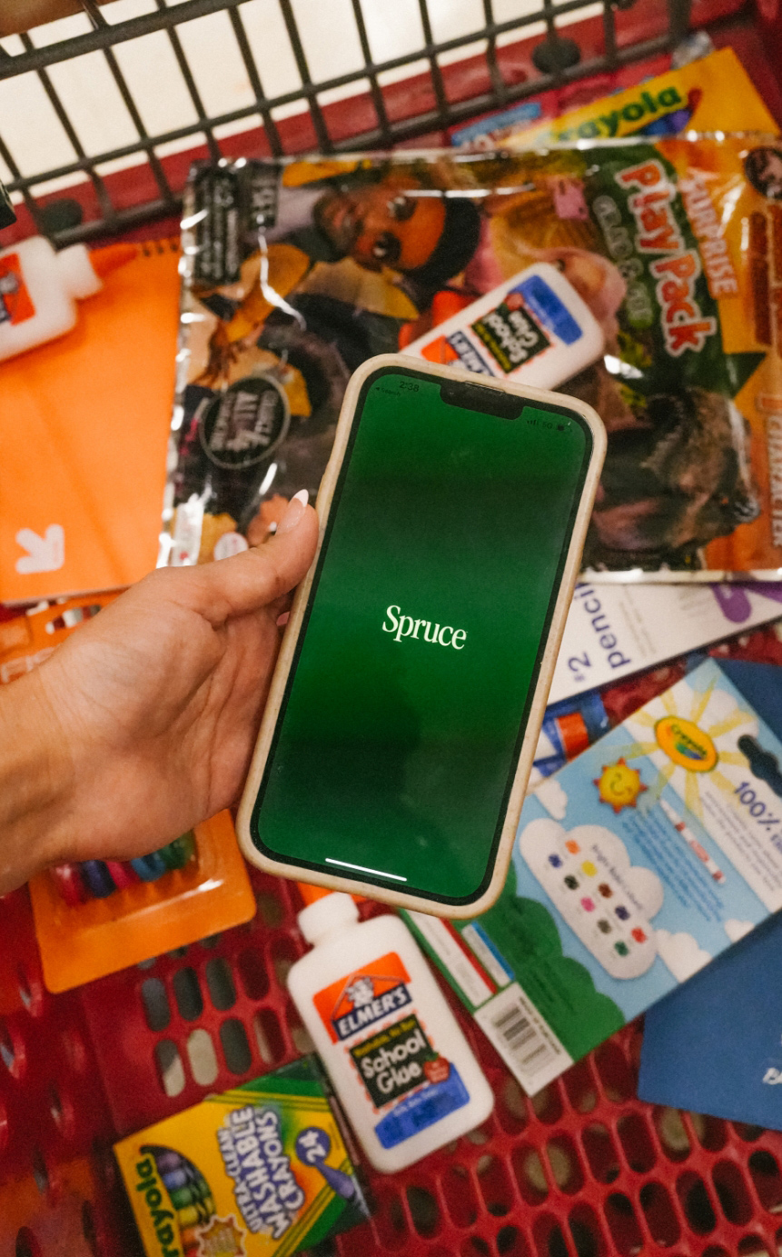 Spruce logo appearing on a cell phone with school supplies in the background.
