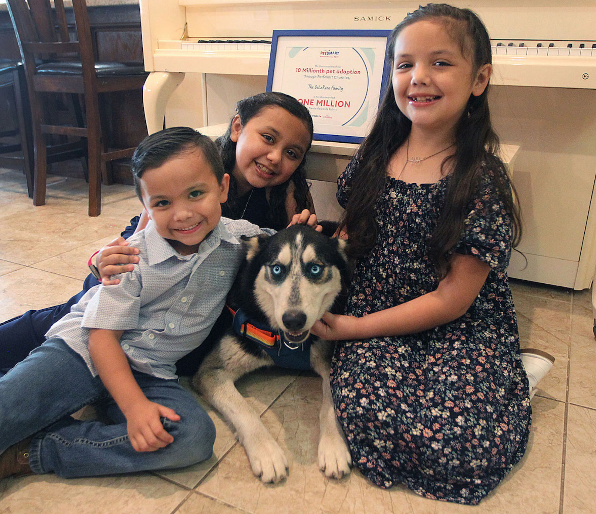 Three kids sitting down with a dog.
